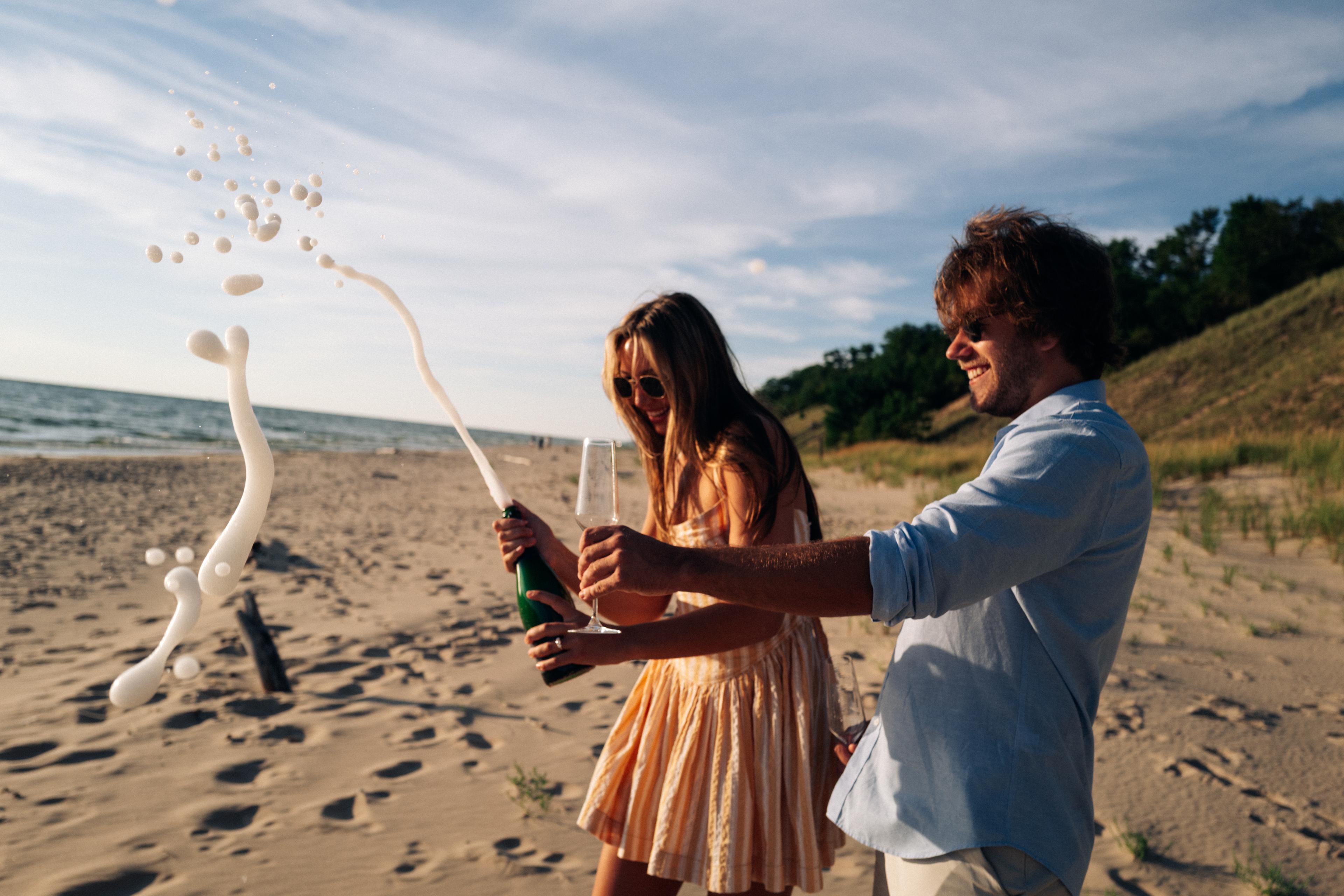 Harry and Lauren raising their glasses on the beach